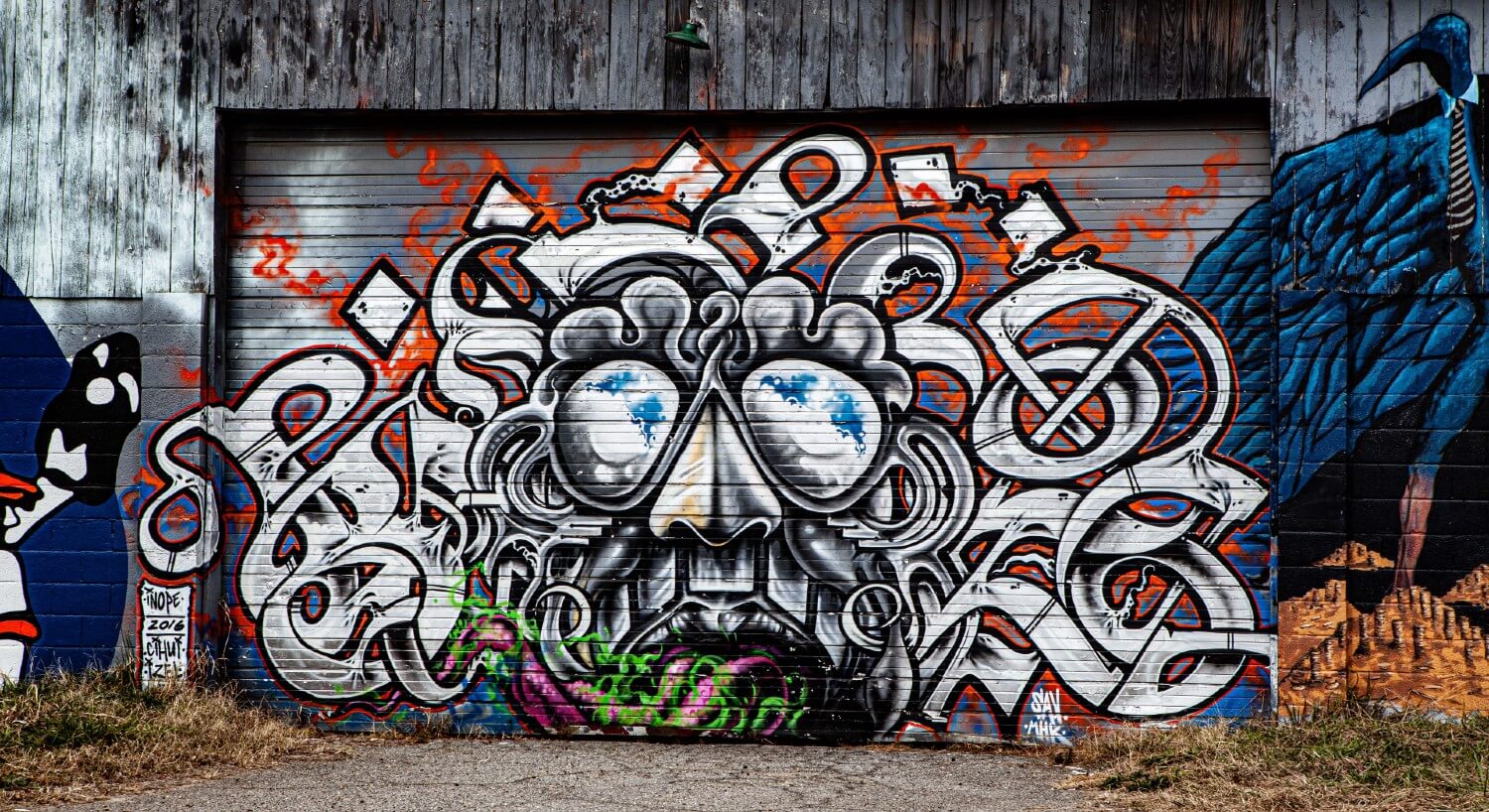 Garage door of a wooden building with mural drawn in graffiti-style