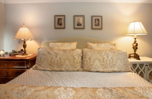 King size bed with upholstered headboard, luxurious linens and bedside table with white lamps