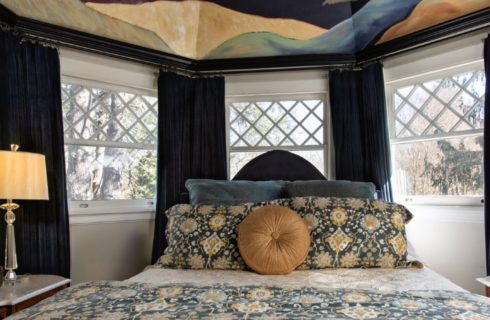 Bedroom with queen bed set within a bay window and a Gaugin-inspired nighttime sky mural overhead