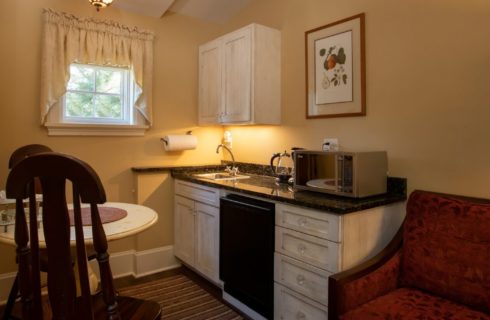 Mini kitchenette with white cabinets, granite countertop and table with two chairs