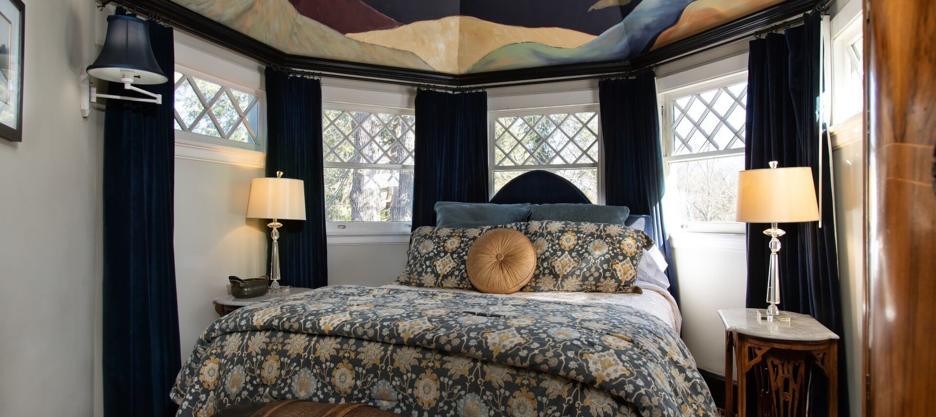 Bedroom with queen bed set within a bay window and a Gaugin-inspired nighttime sky mural overhead