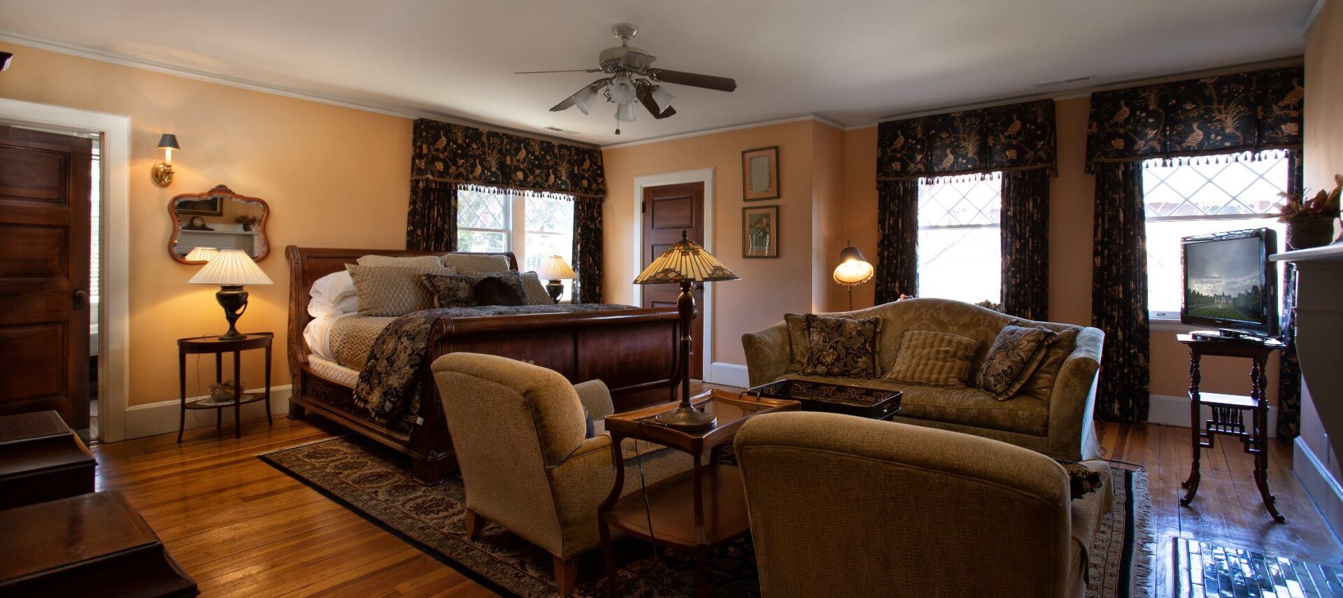 Spacious guest room with magnificent king-size sleigh bed and sitting area with a couch and two chairs